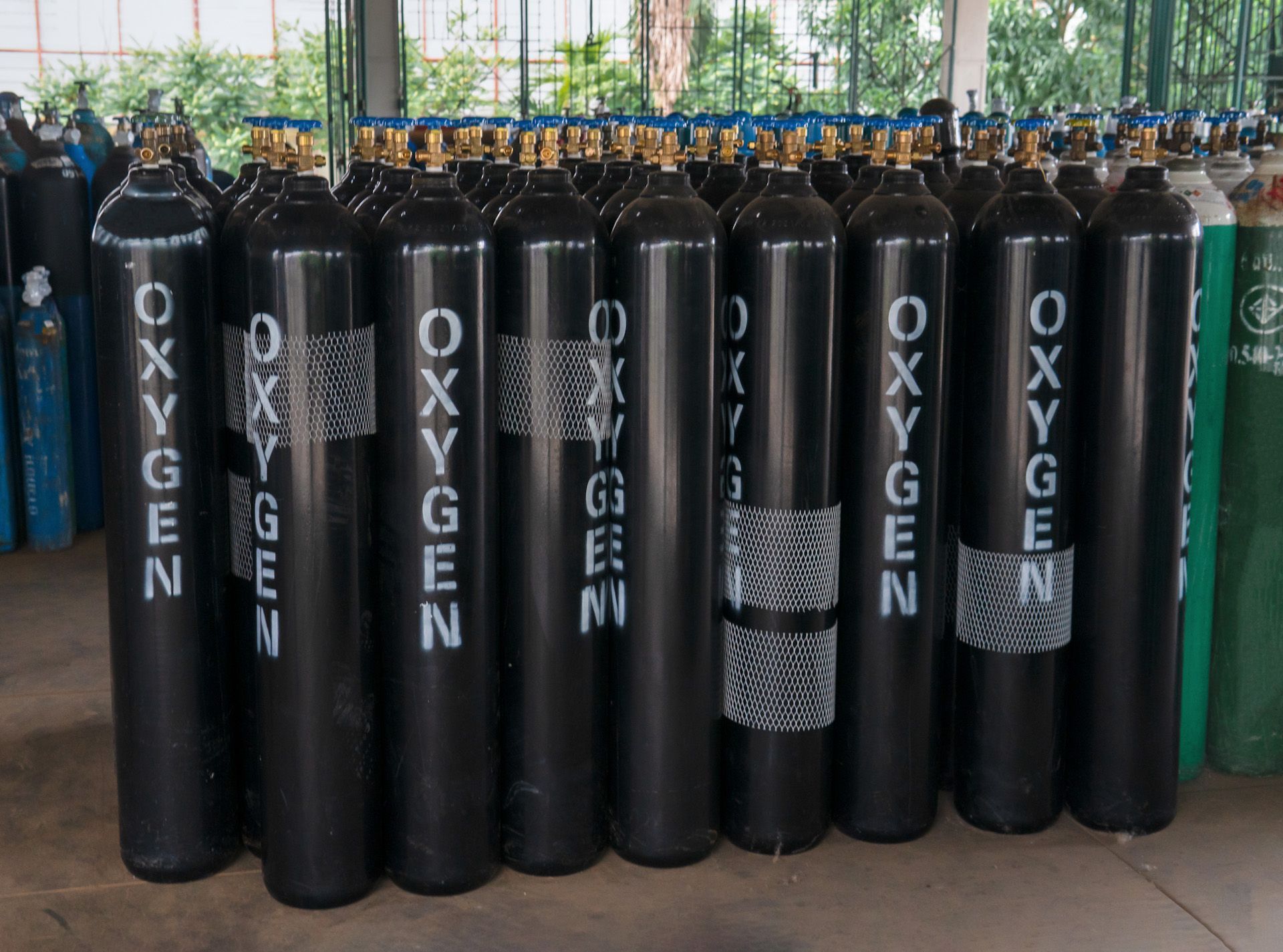 A row of oxygen cylinders are lined up in a warehouse