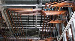 A bunch of copper pipes are hanging from the ceiling of a building.