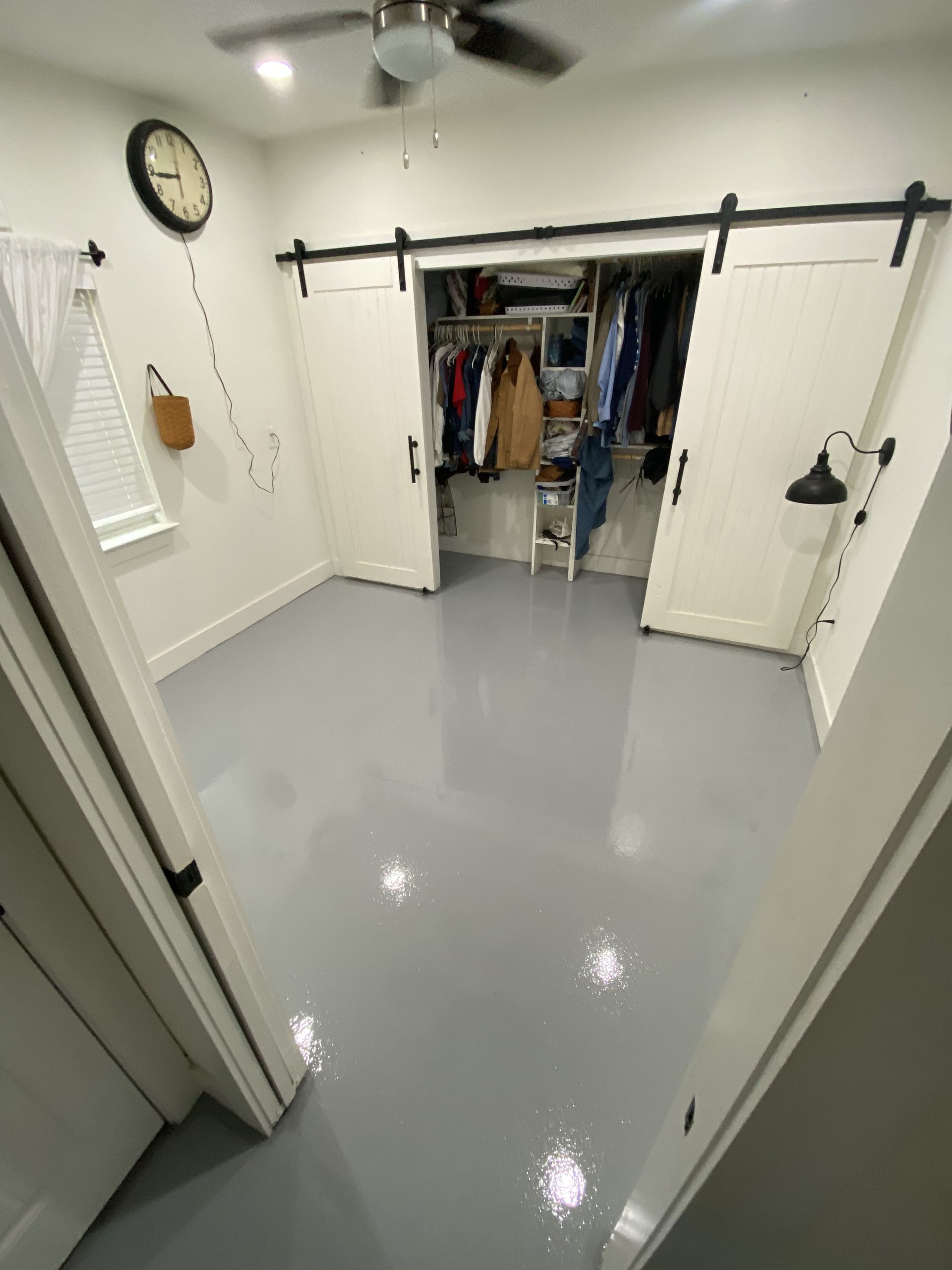 Room with gray floor, white walls, closet with sliding doors, and ceiling fan.