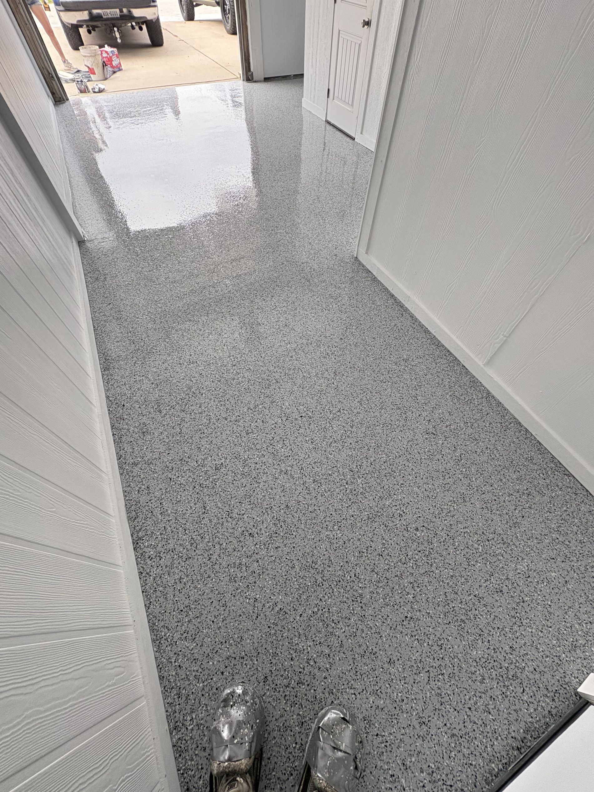 Gray speckled epoxy flooring in a narrow hallway, leading to an unknown exterior.