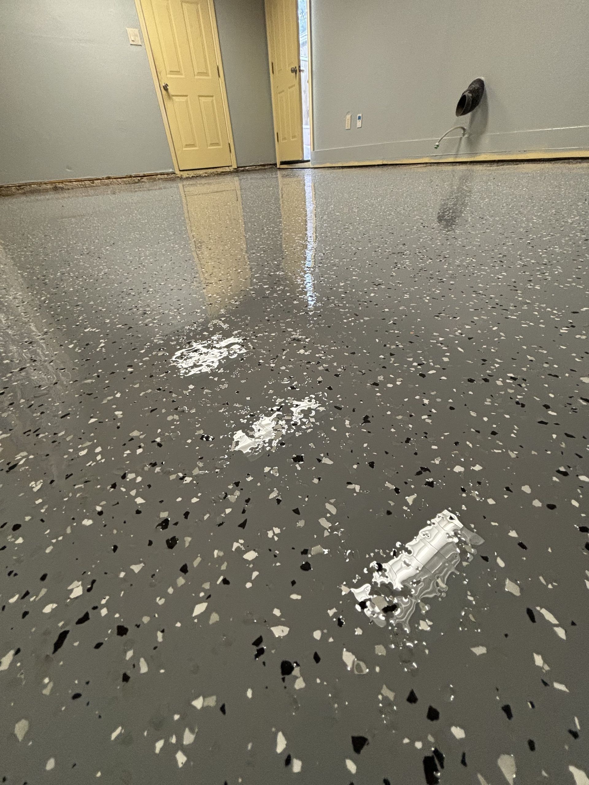 Gray speckled epoxy floor with white puddles reflecting light.