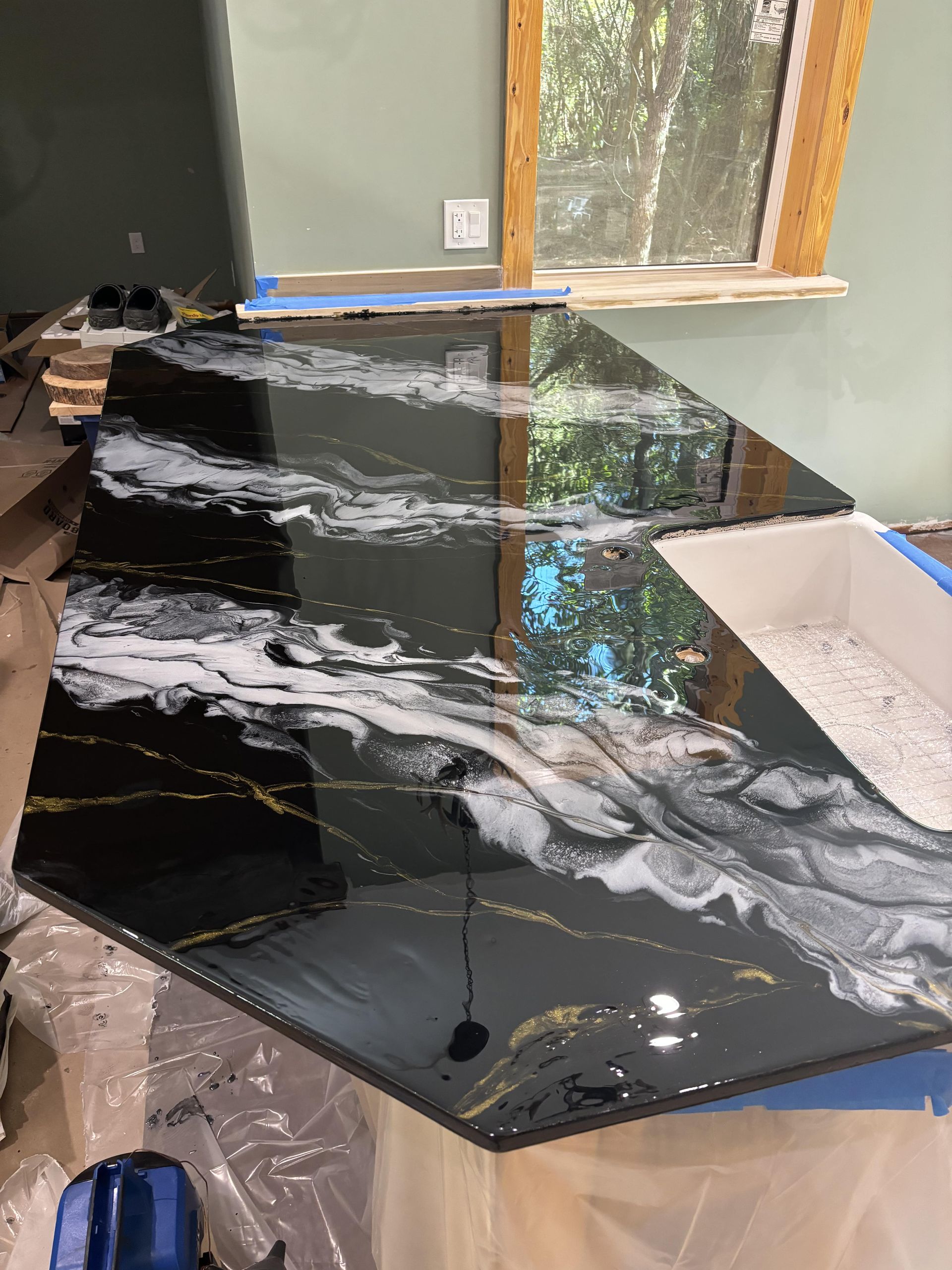 Black countertop with white and gold marbling, set in a room with a window.