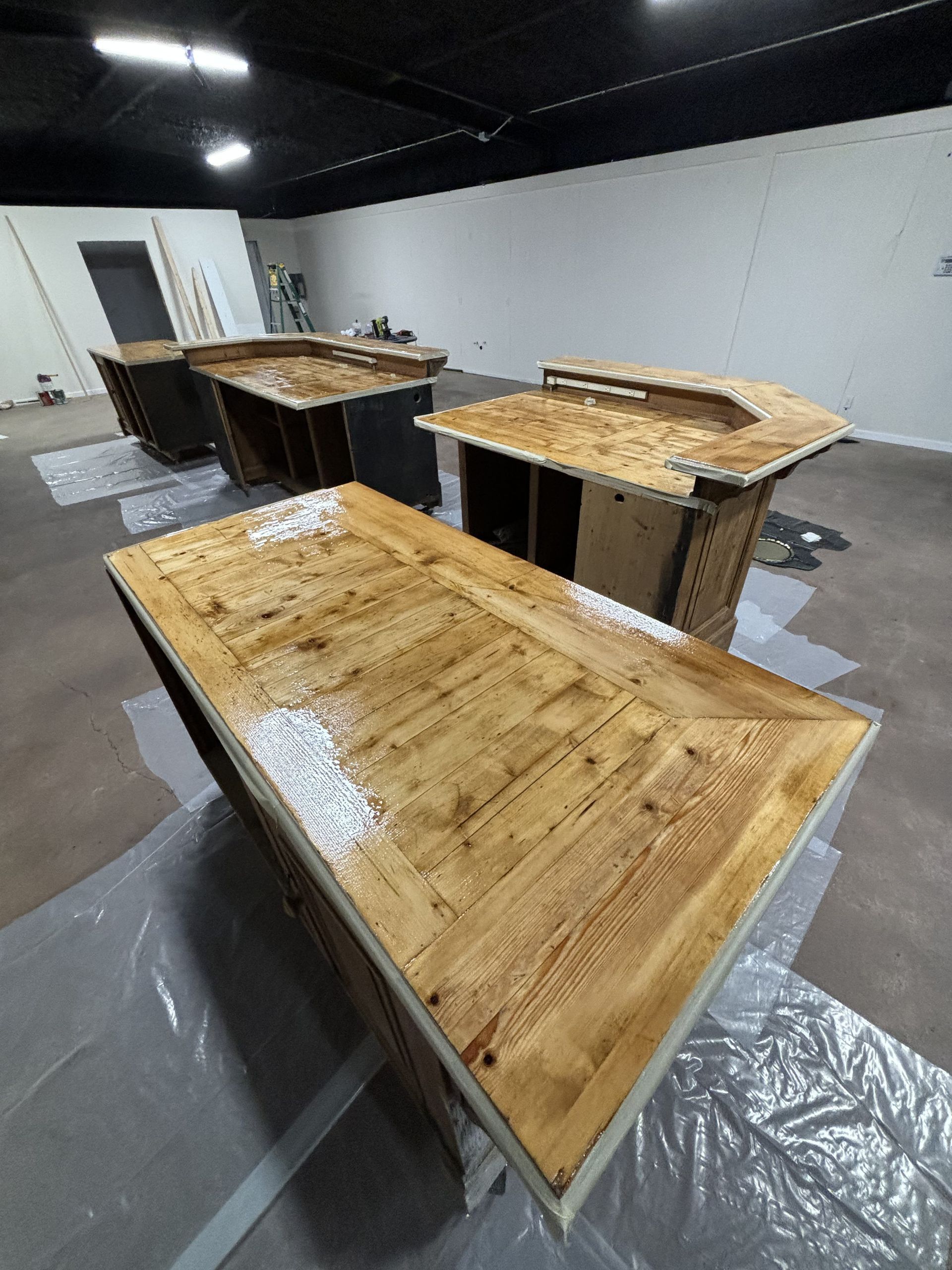 Four wooden bar-like structures in a room. The closest one is coated in light-colored varnish.