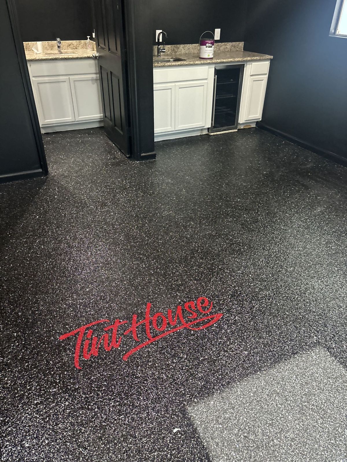 Epoxy floor with logo, wet bar, and black walls; interior.