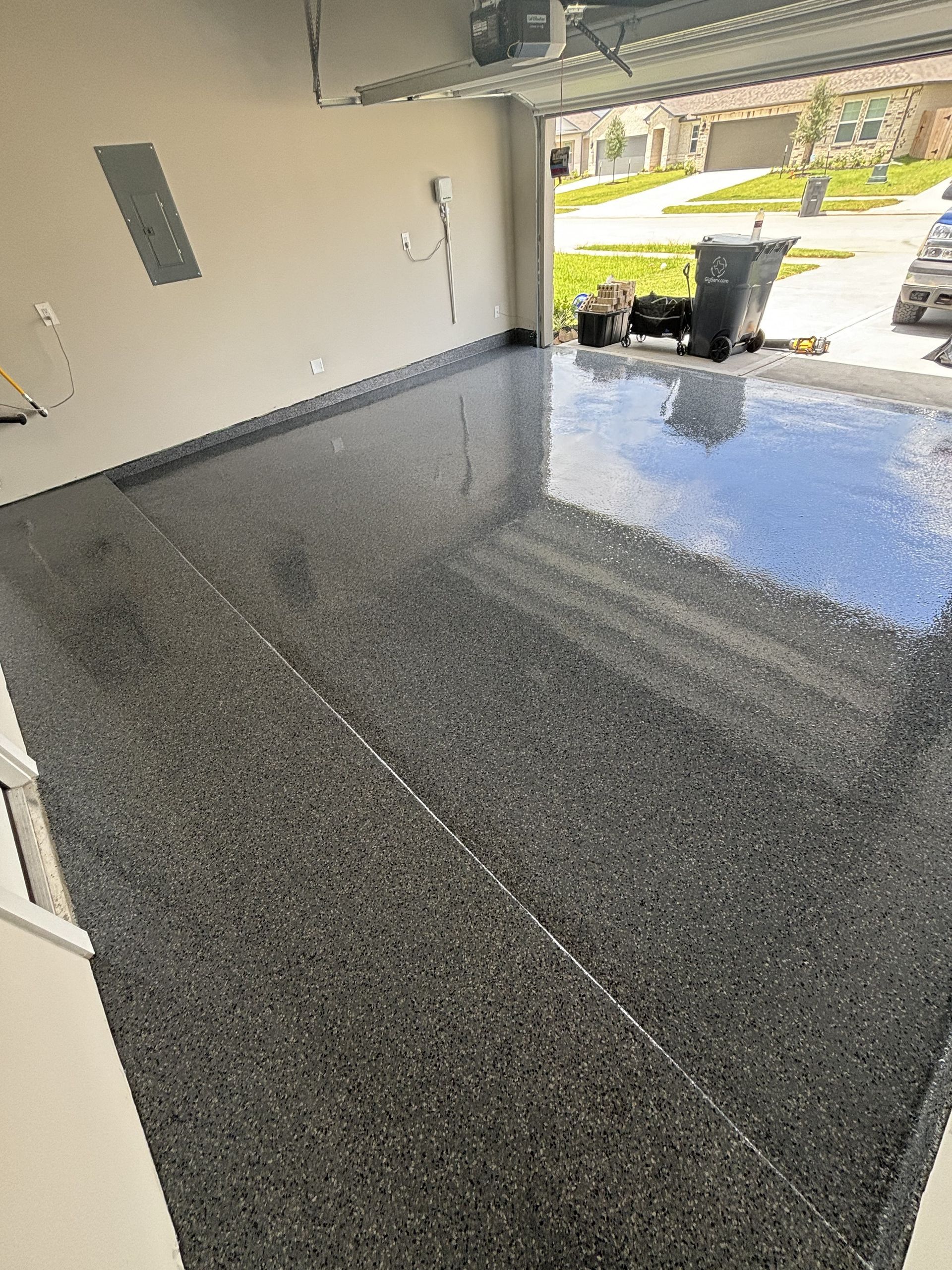 Garage with a speckled epoxy floor, open doorway, and a view of the outside.