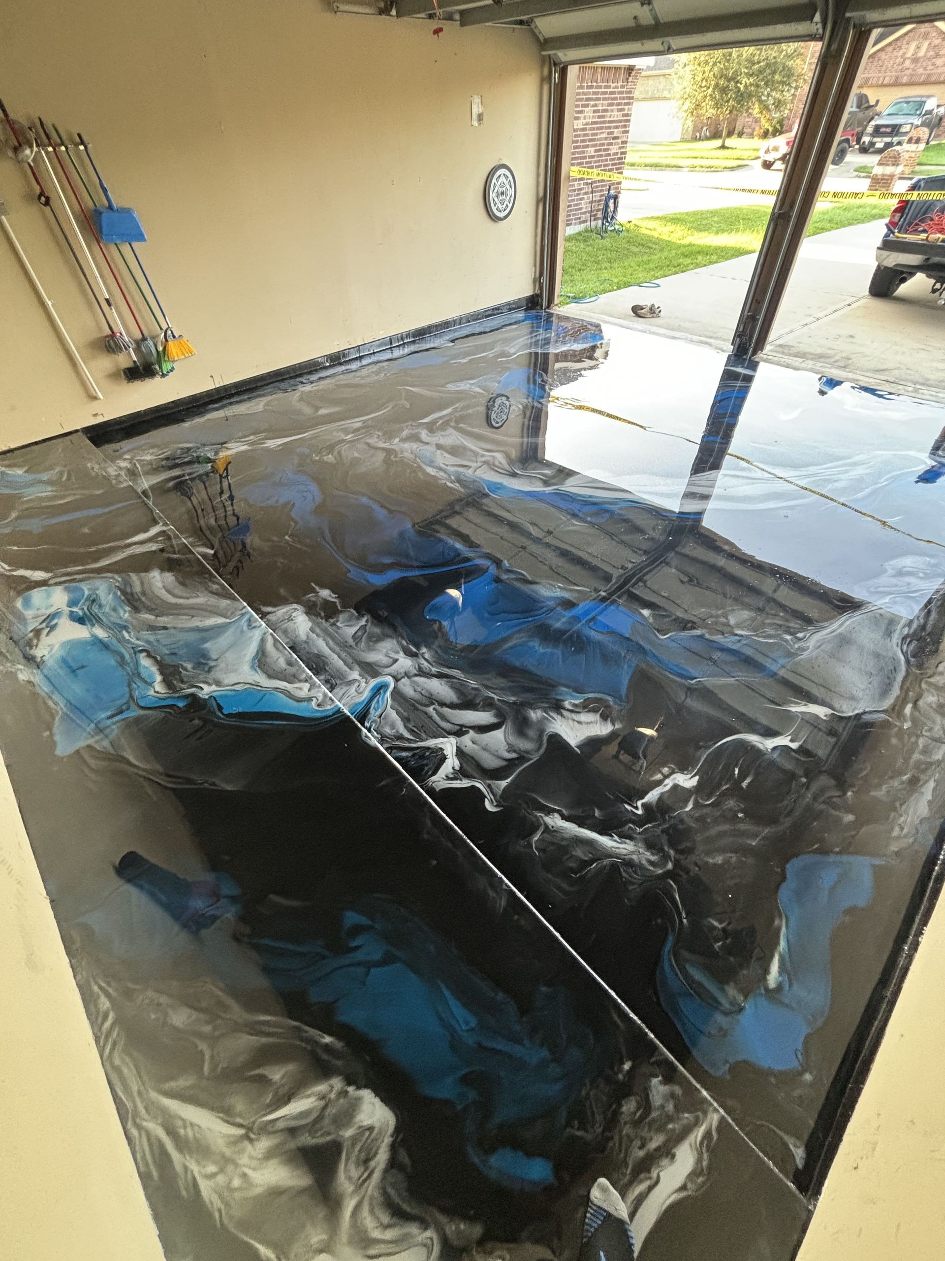 Garage floor being coated with a black and blue epoxy finish.