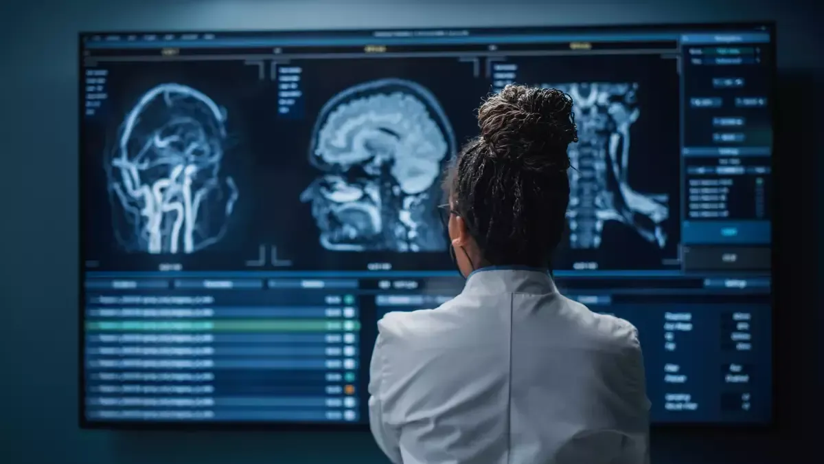 A woman in a lab coat is looking at a mri of a person 's brain.