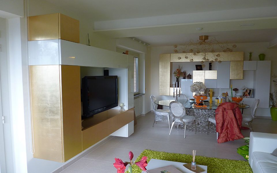 salotto e sala da pranzo con arredi bianchi e dorati