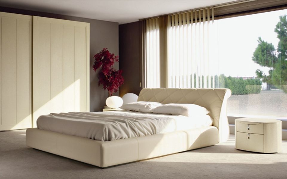 camera con letto beige in pelle e ampia finestra