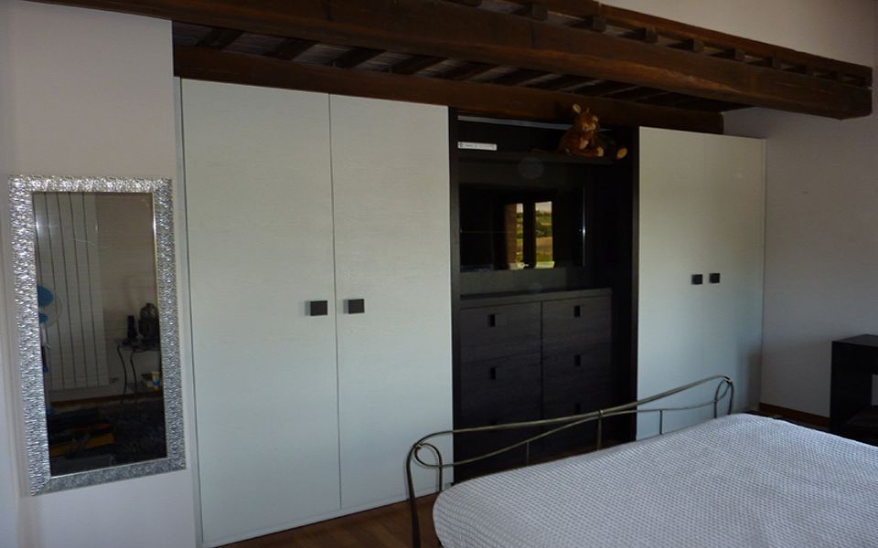 parete attrezzata con armadi bianchi e cassetti neri