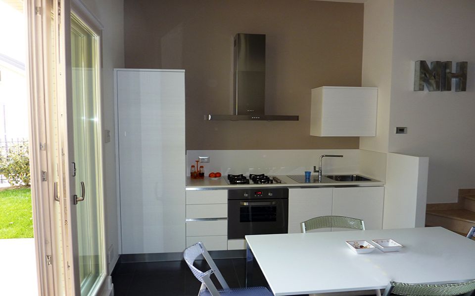 cucina piccola con arredi bianchi e porta finestra