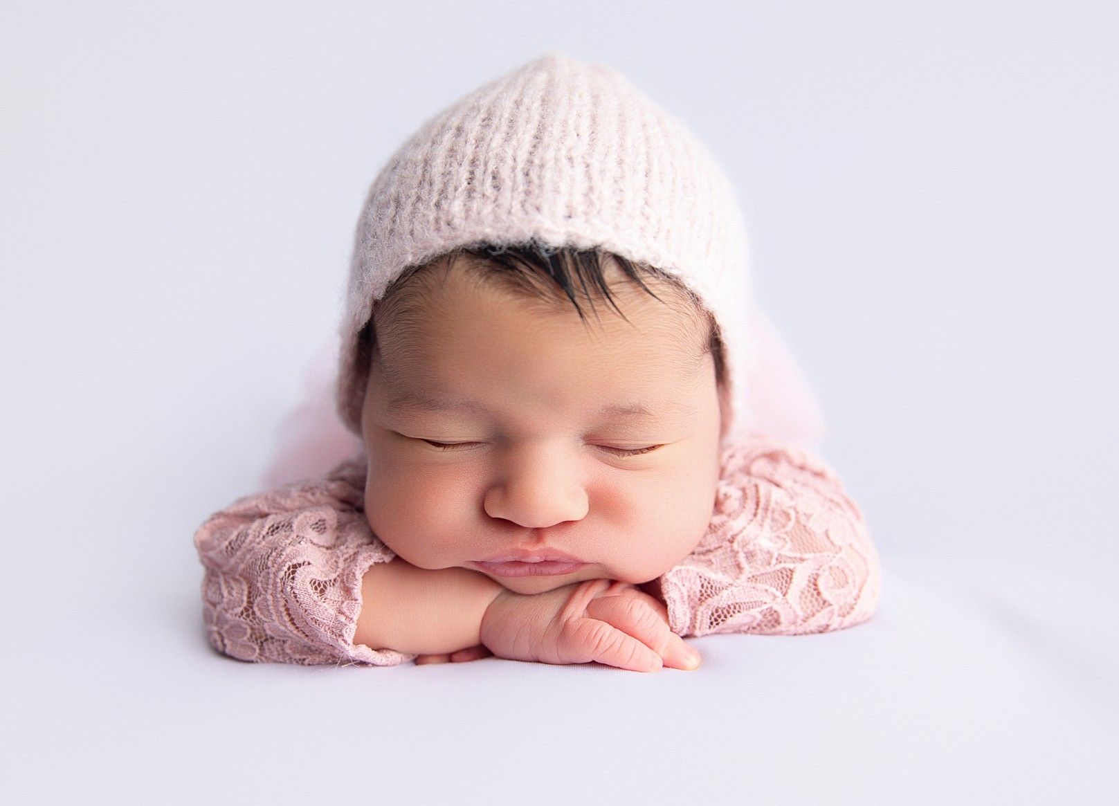 Sleeping newborn baby wrapped in soft blush tones, photographed in a calm, baby-led newborn portrait session in Mokena, Illinois.