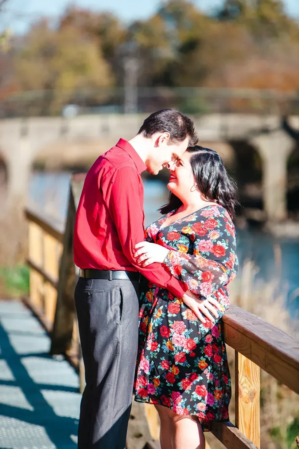 couple embracing on a wooden bridge by a river