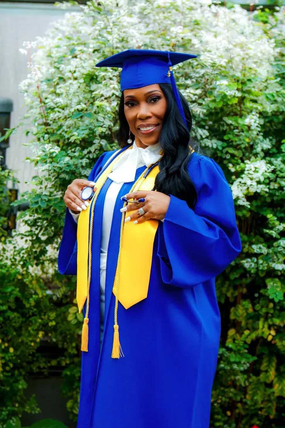 woman in blue graduation gown in green foliage