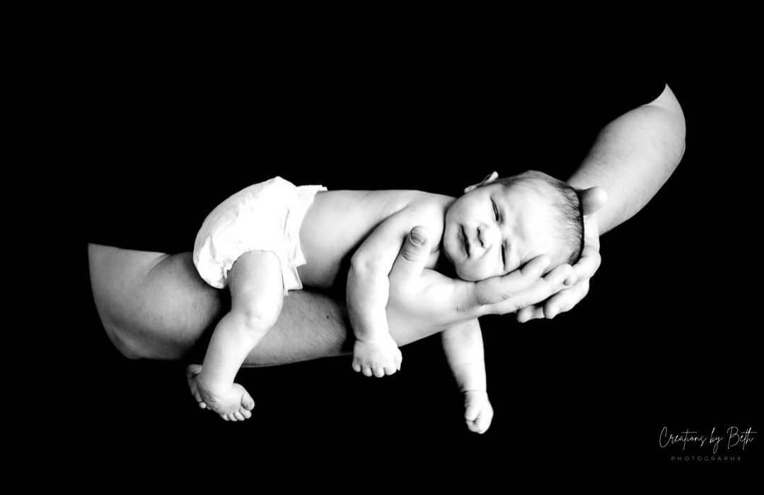 A black and white photo of a baby sleeping in a woman 's hands.