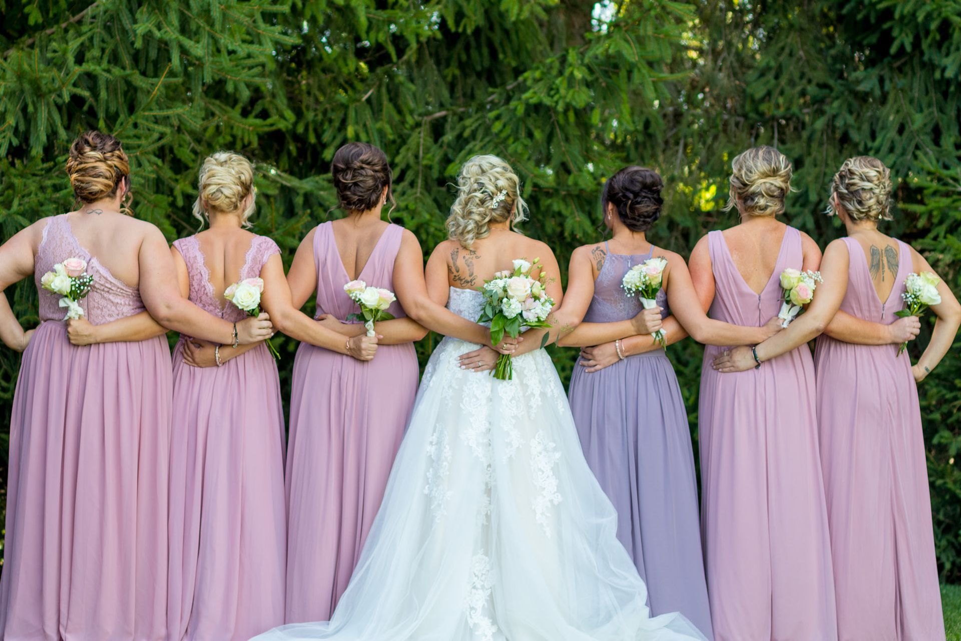 bride in white gown stands with bridesmaids