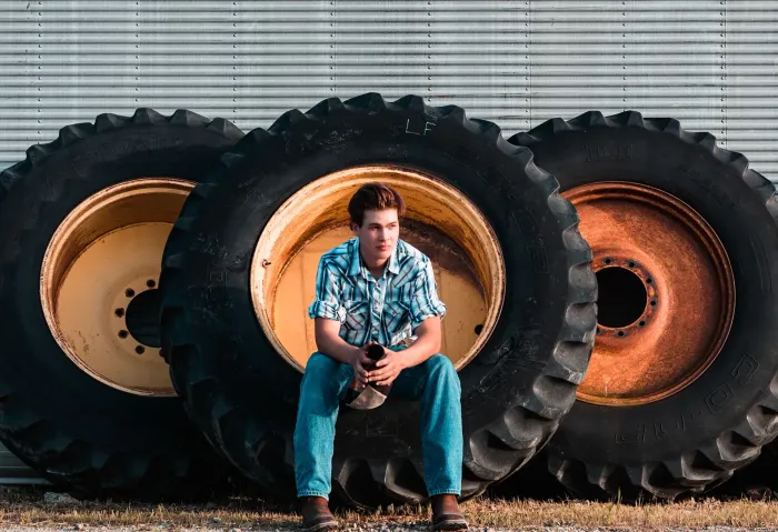 A young man is sitting on a pile of tractor tires for branding Photography in Mokena, IL