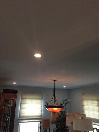 Interior room view with recessed lighting, chandelier, and window shades.