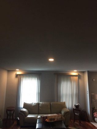 Living room with a couch, windows with blinds, and recessed lighting.