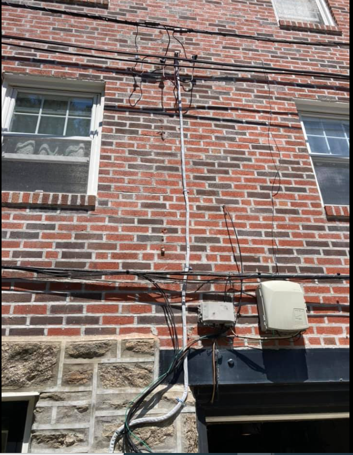 Brick building exterior with windows, power lines, and electrical boxes.