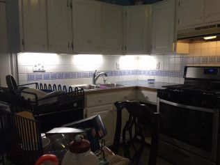 Kitchen with white cabinets, blue and white tiled backsplash, and stainless steel appliances.
