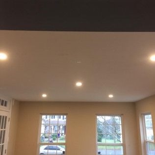 Ceiling with recessed lights, windows, and light-colored walls. A car is visible outside a window.