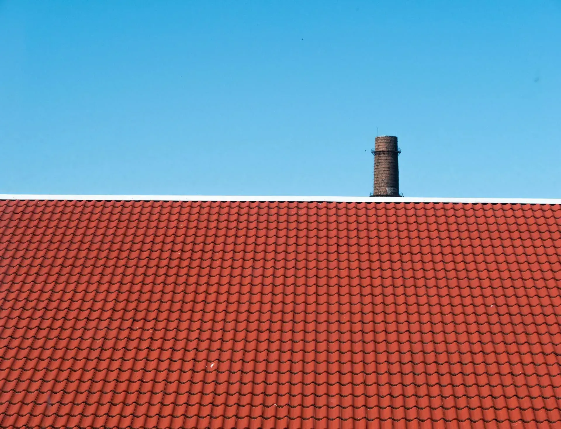 A red tiled roof with a chimney on top of it.