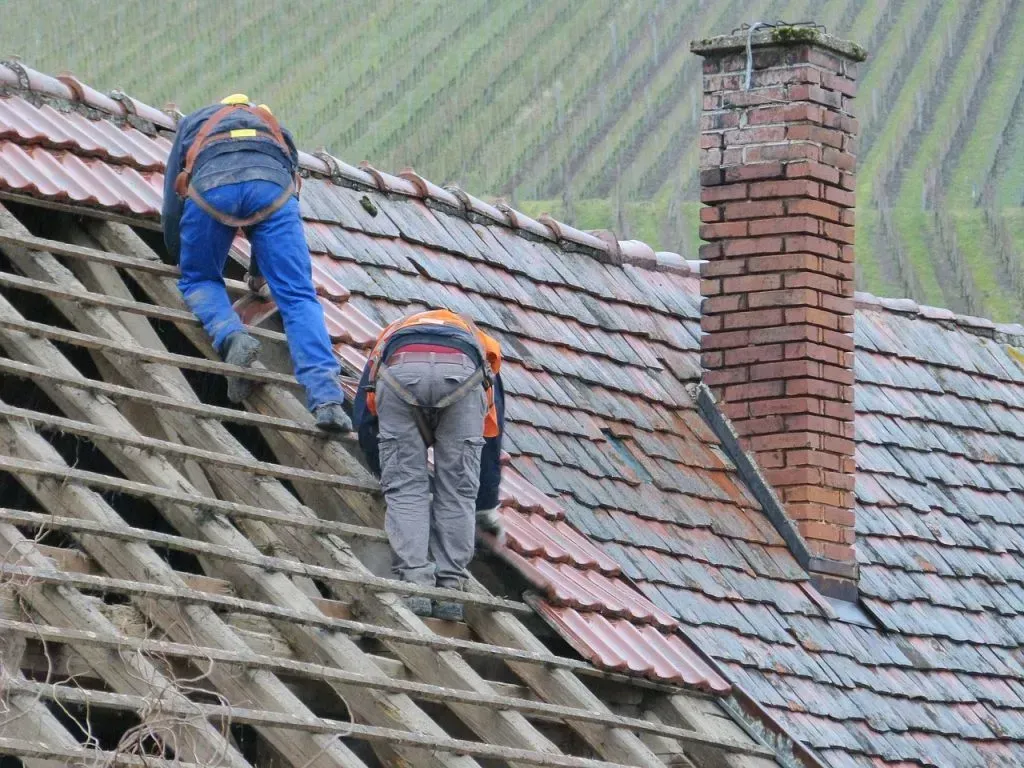 Two men are working on the roof of a house.