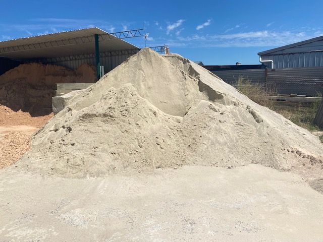 A Pile Of Sand Is Sitting In Front Of A Building — DHM Sand, Gravel & Soil Supplies in Sebastopol, VIC
