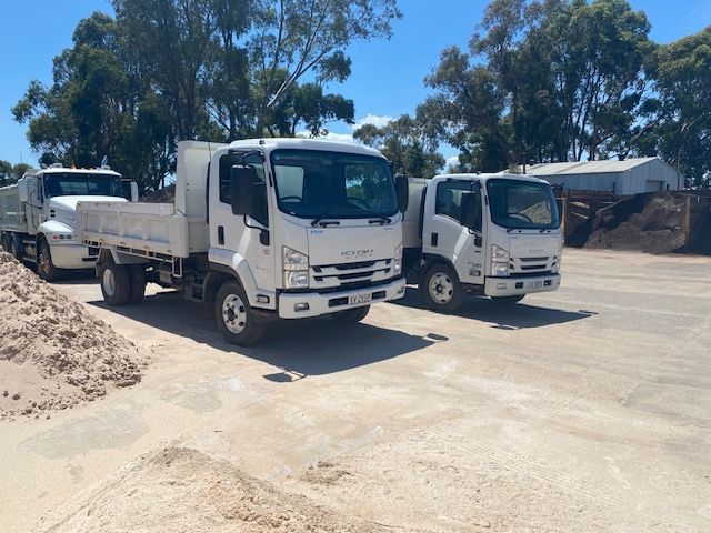 Three White Trucks Are Parked Next To Each Other On A Dirt Road — DHM Sand, Gravel & Soil Supplies in Sebastopol, VIC