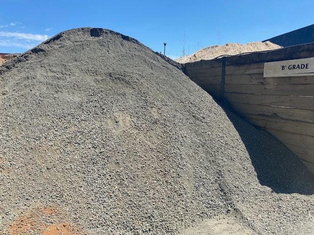 A Pile Of Gravel Is Sitting Next To A Wooden Fence — DHM Sand, Gravel & Soil Supplies in Sebastopol, VIC