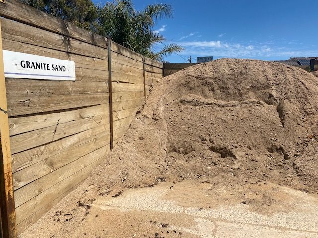 A Pile Of Sand Is Sitting Next To A Wooden Fence — DHM Sand, Gravel & Soil Supplies in Sebastopol, VIC