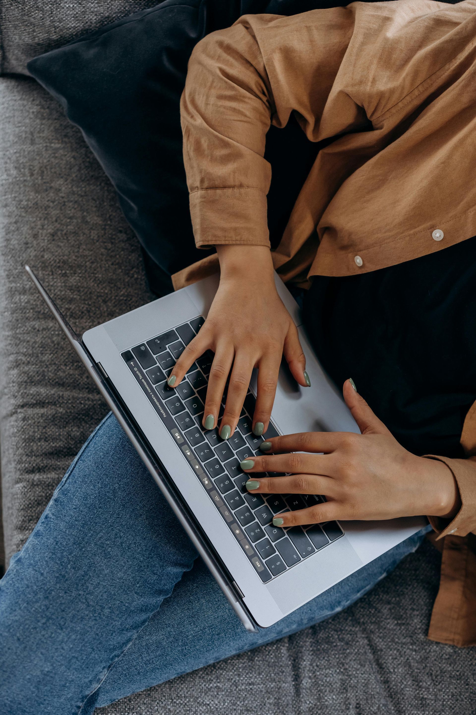 A man with a beard is sitting at a desk using a laptop computer.