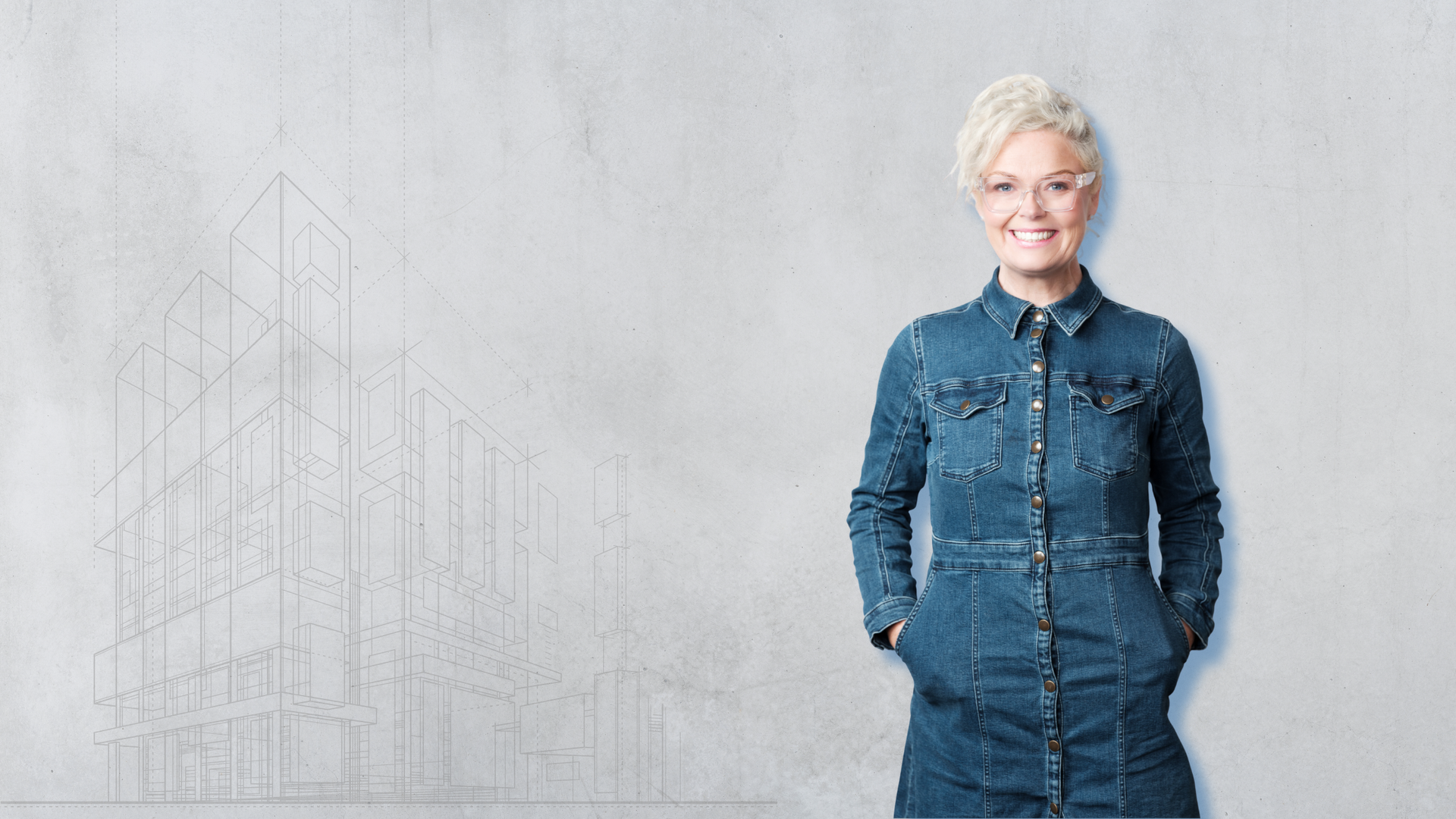 Woman in denim dress smiling, standing against a textured gray wall with sketched architectural outlines.
