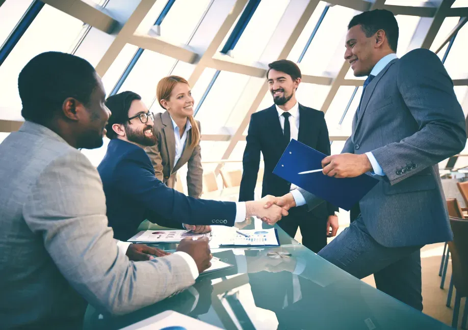 A group of business people are shaking hands in a conference room.