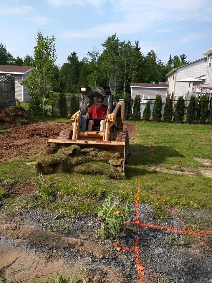 A man is driving a bulldozer in a grassy field.