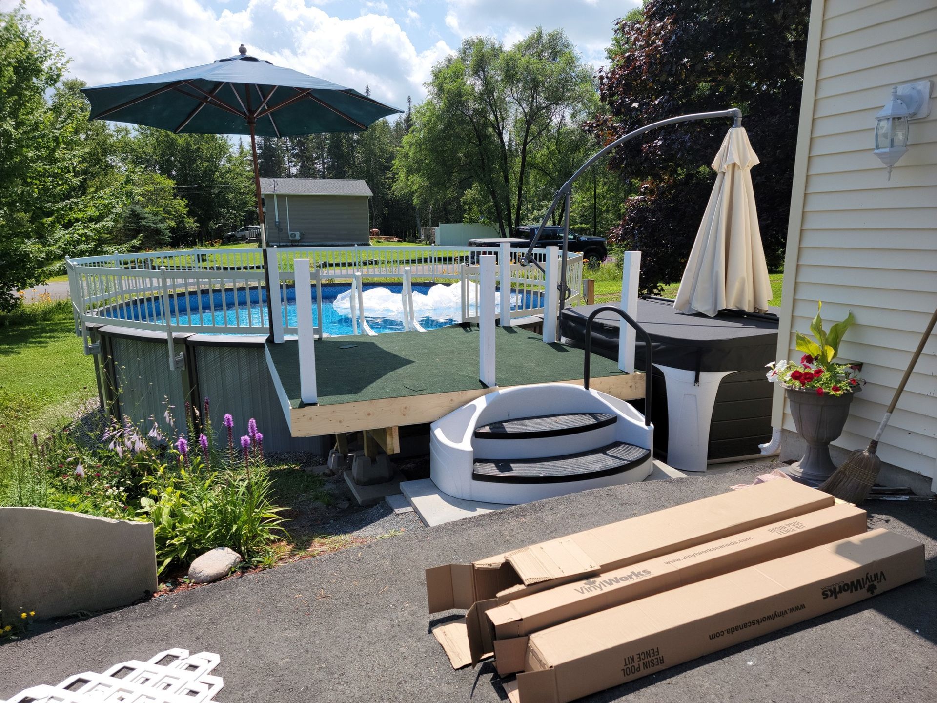 A swimming pool is surrounded by a deck with boxes and umbrellas.