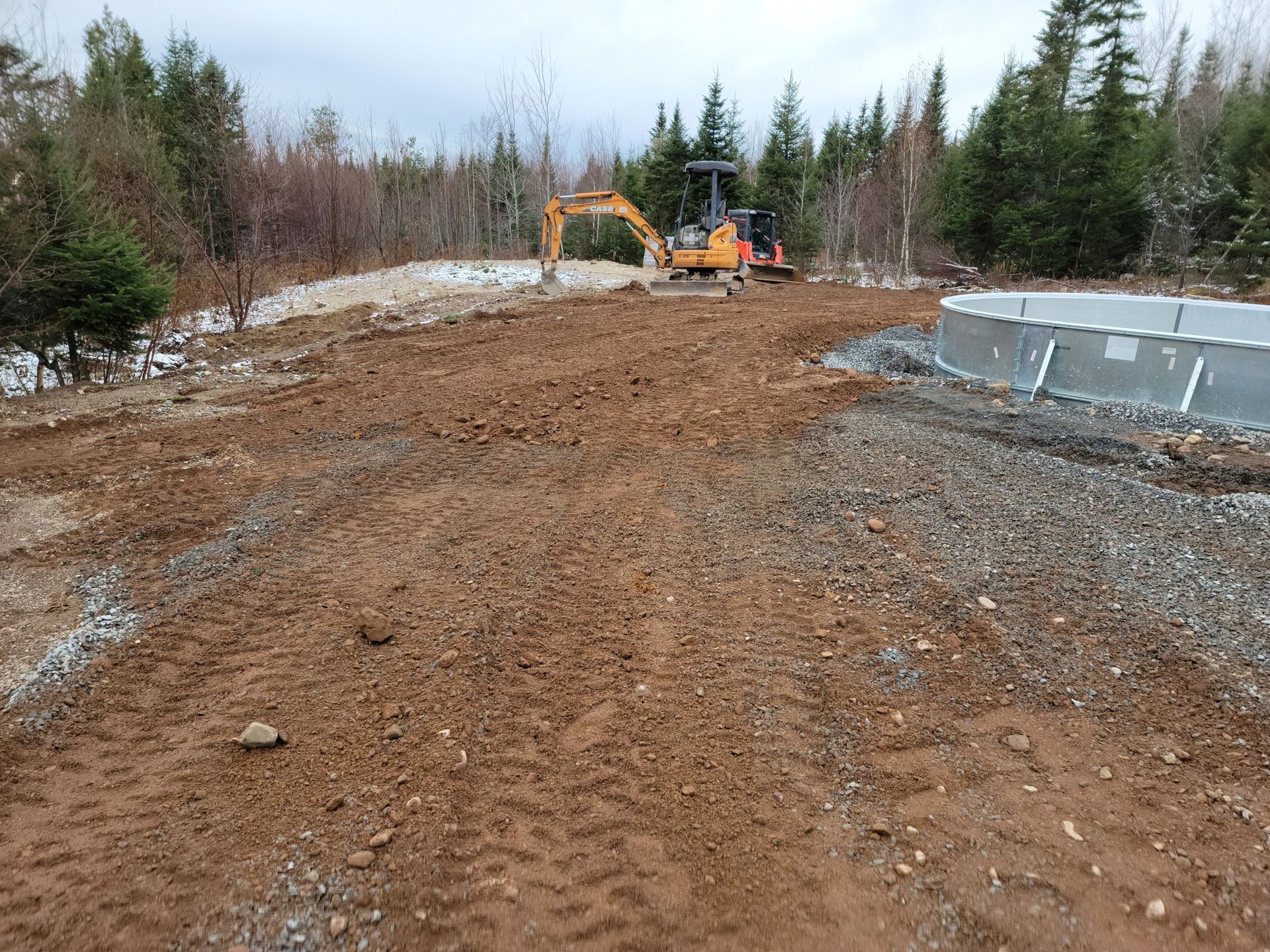 A construction site with a pool in the background and a bulldozer in the foreground.