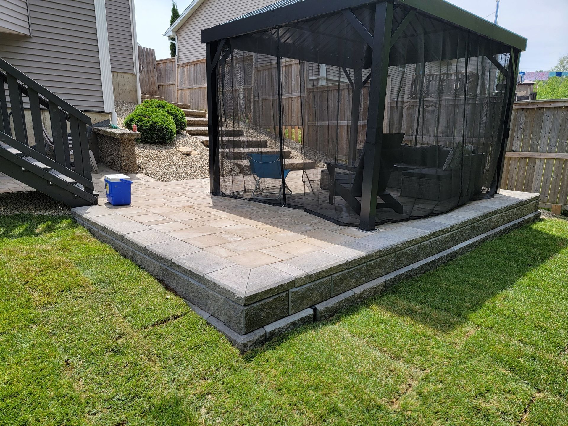 A gazebo with a screened in area in the backyard of a house.