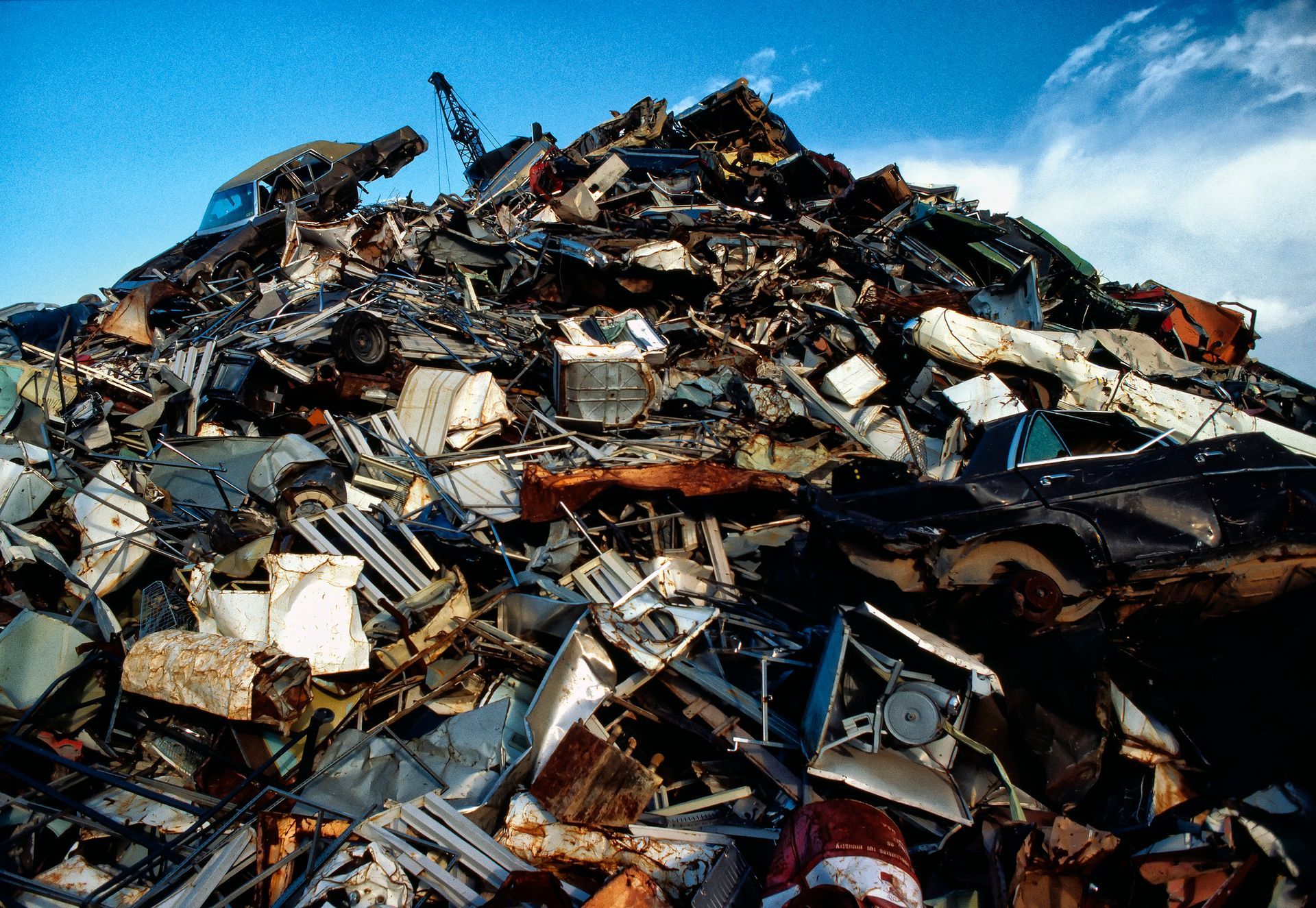 A pile of scrap metal, including car parts and appliances, representing scrap metal recycling.