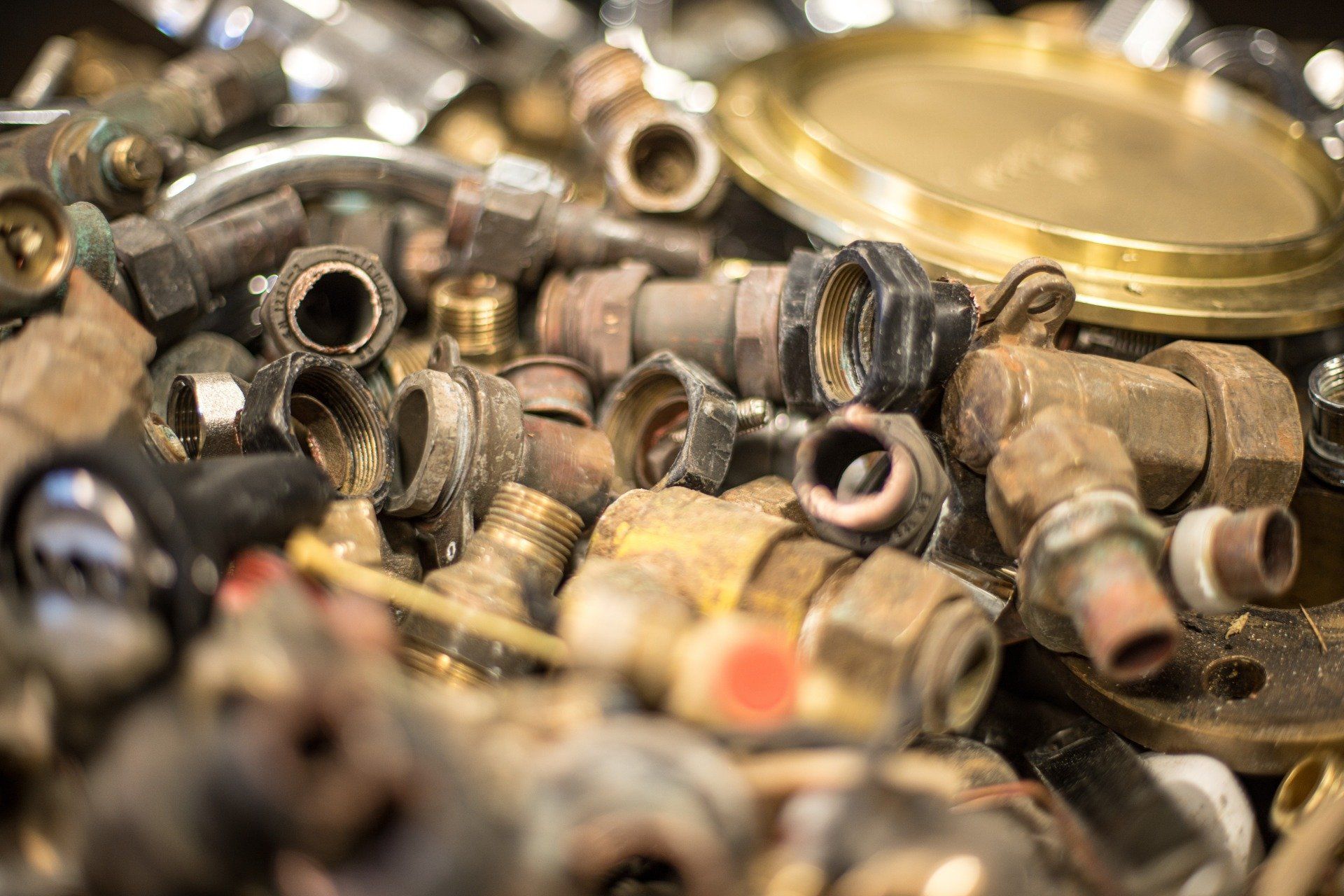A pile of rusty brass pipes and valves on a table.