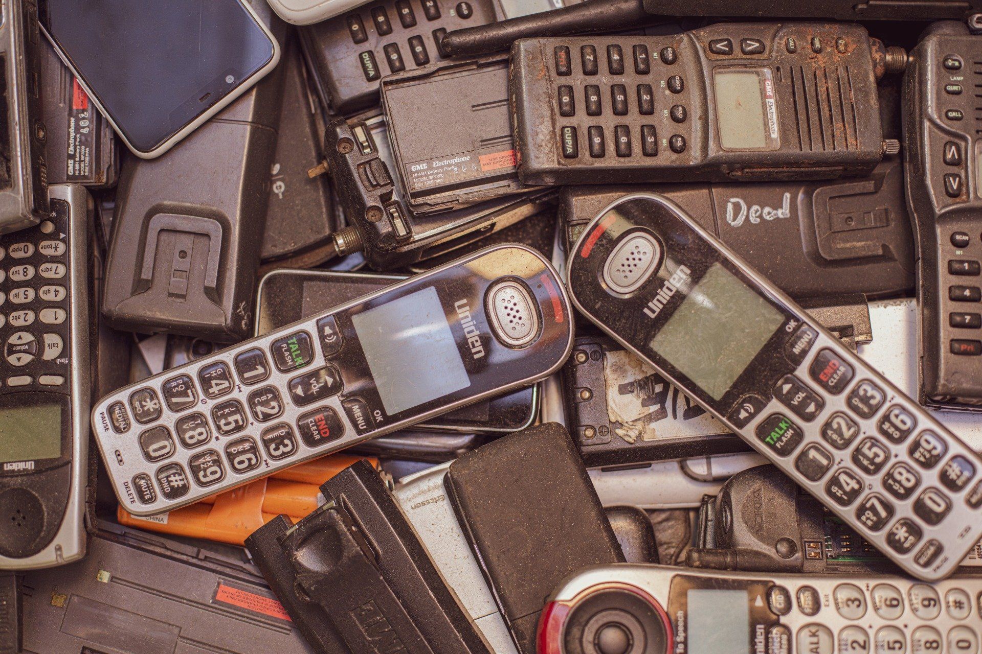 A pile of old cell phones on a table.