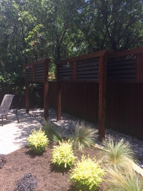 Wooden fence with horizontal slats, a backyard setting with landscaping.