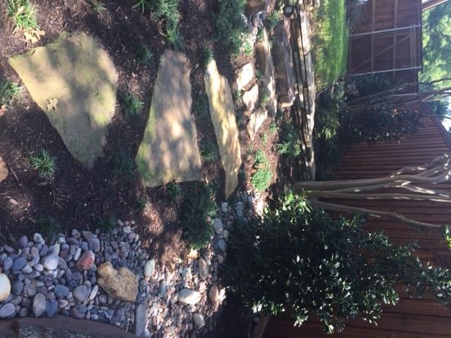 Flagstone path and rock garden next to a wooden fence.