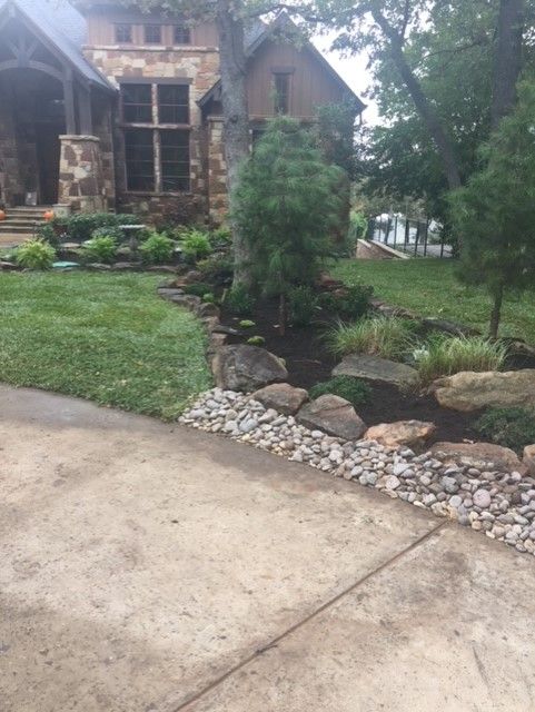 Stone house with lush landscaping, pathway, and gravel border.