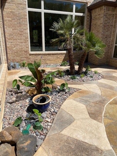 Brick house exterior with stone path, small garden with palms and banana plant.