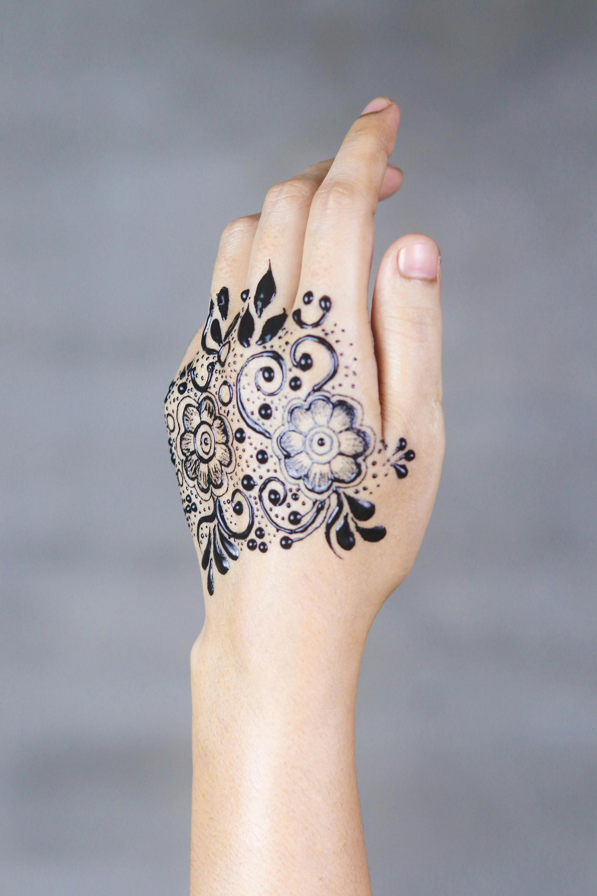 A woman 's hand with a henna tattoo on it.