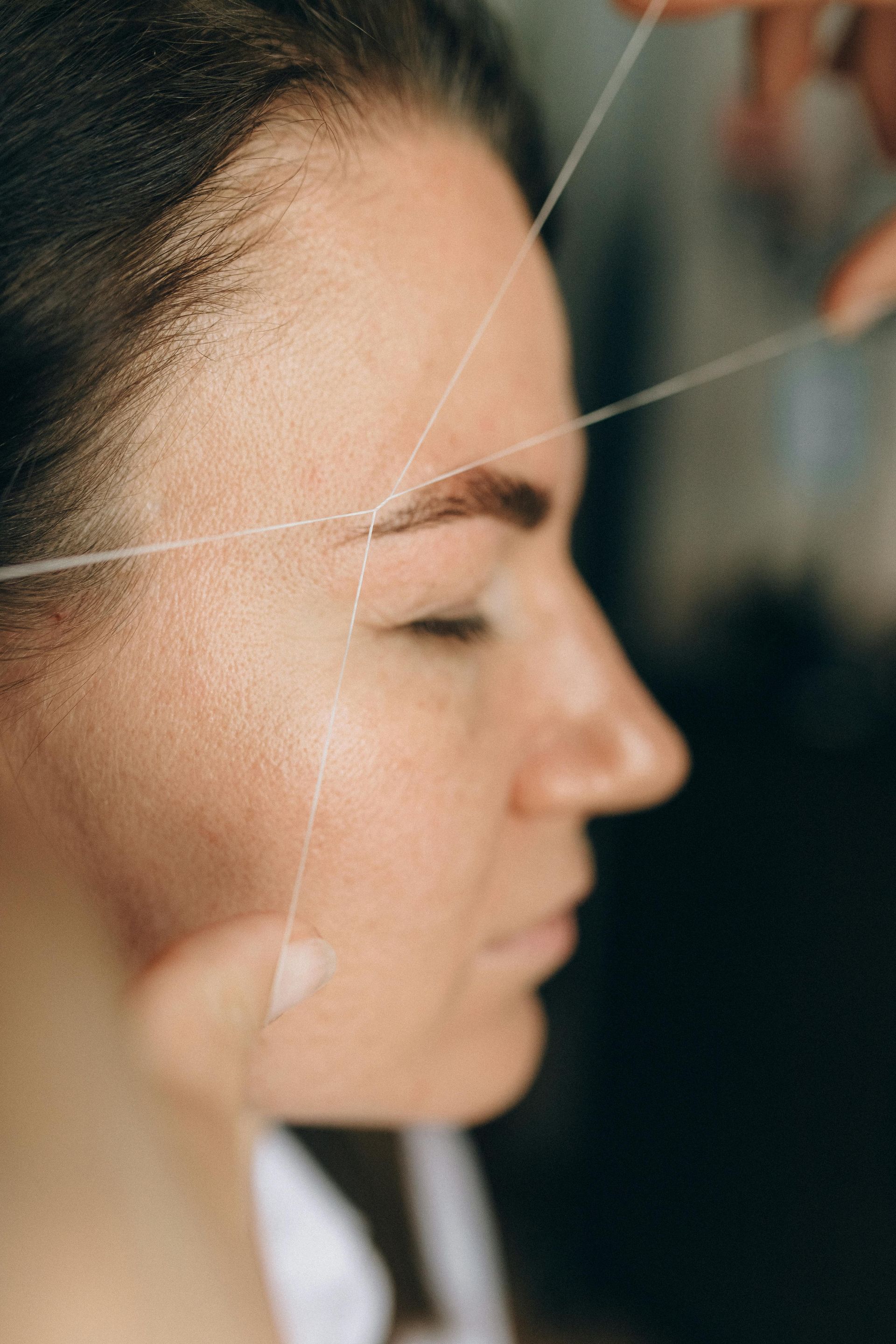 A close up of a woman getting her eyebrows threaded.