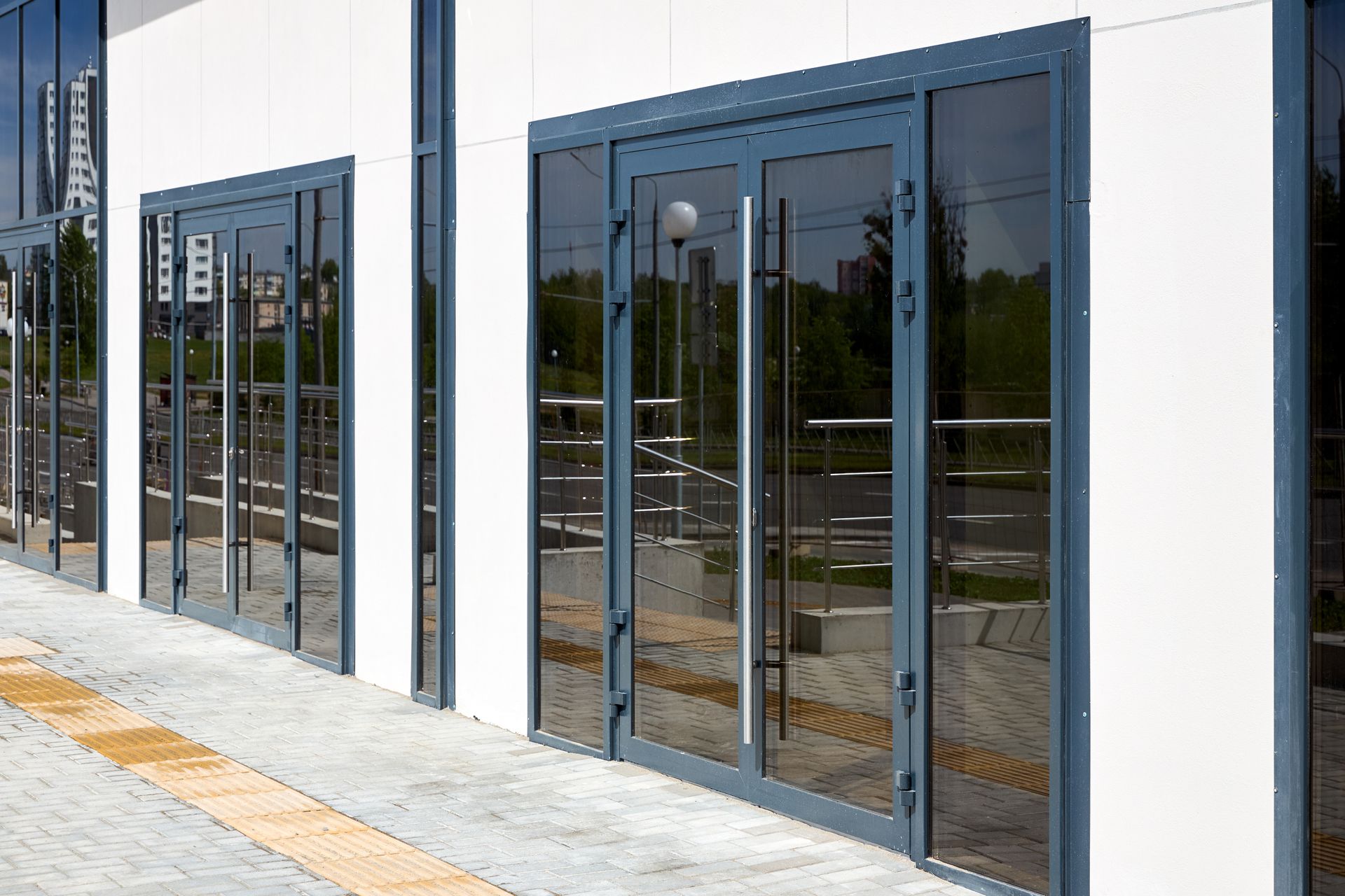 Modern building entrance with dark glass doors and reflective windows along a sidewalk