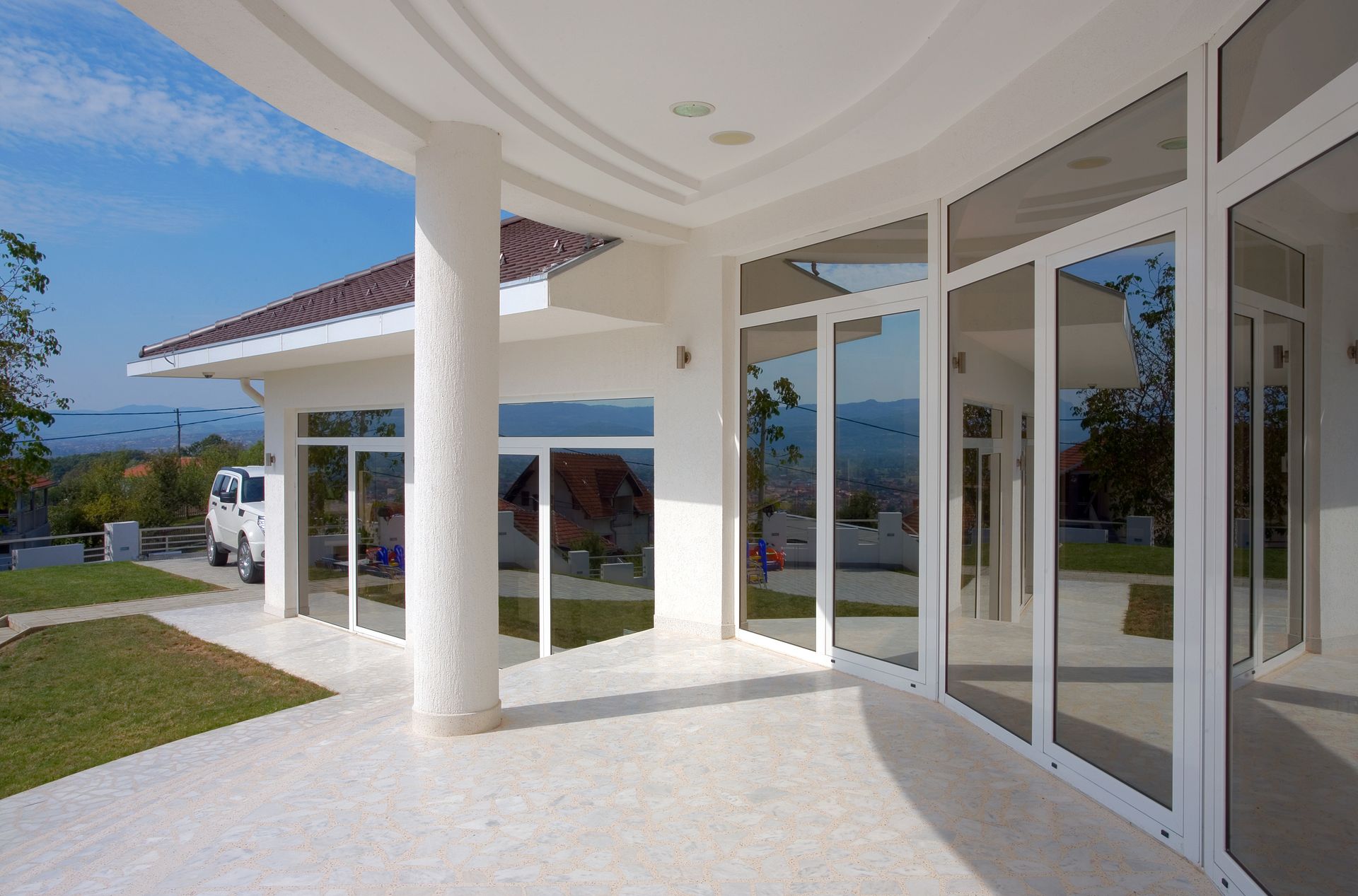 Modern white house patio with glass doors, columns, and ocean view
